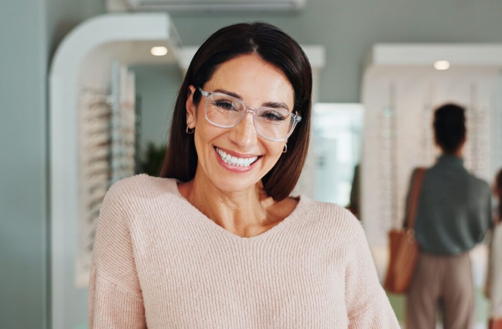Person smiling while wearing new designer glasses in an optometry clinic setting.