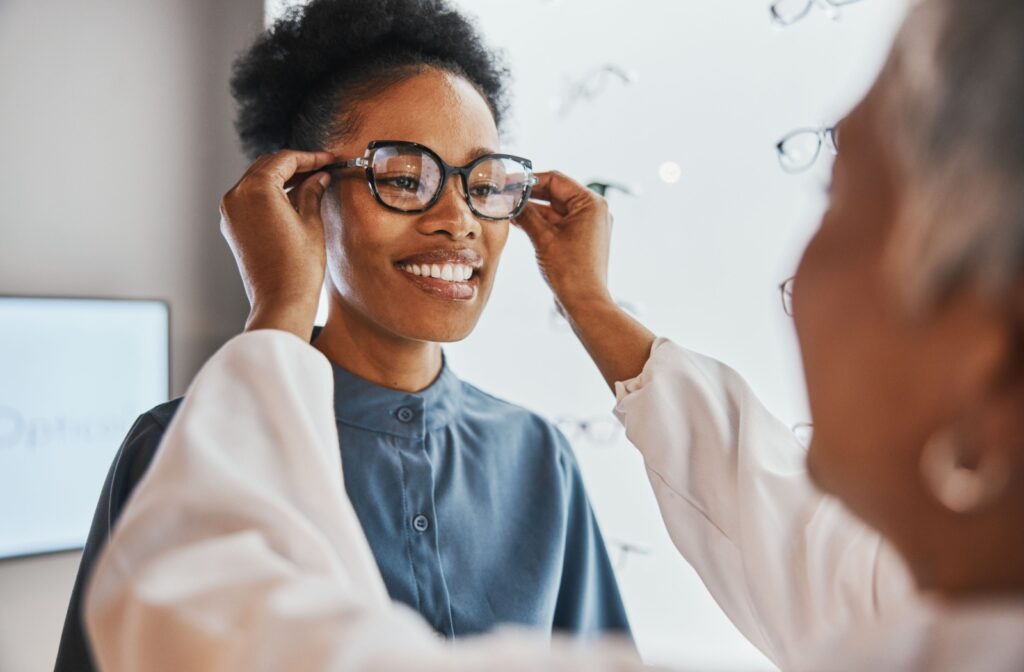 An optician putting a pair of glasses on a persons face